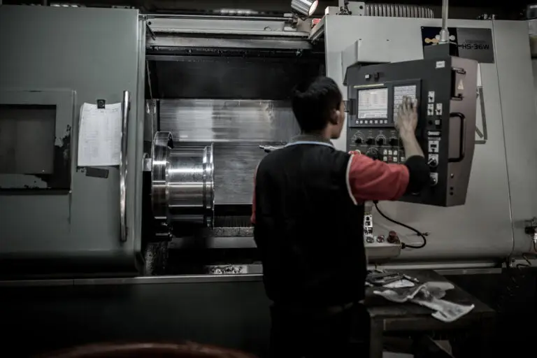 Worker operates lathe with forging in the machine