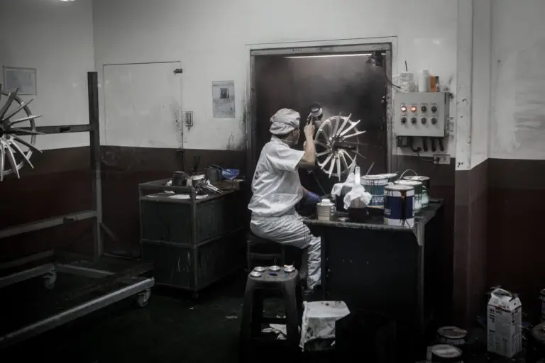 Worker laying base coat on wheel face