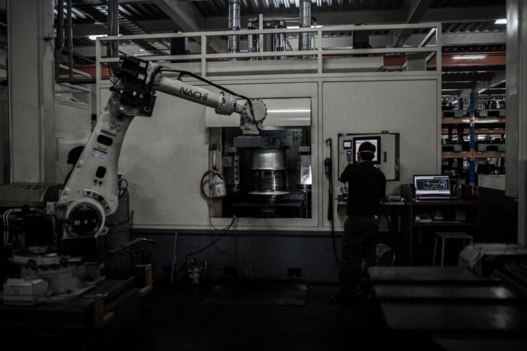 Robotic arm grabbing the forging in the lathe
